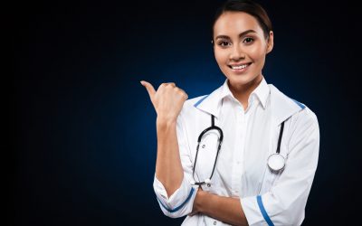 Young happy lady with stethoscope looking camera and pointing at copy space isolated over black